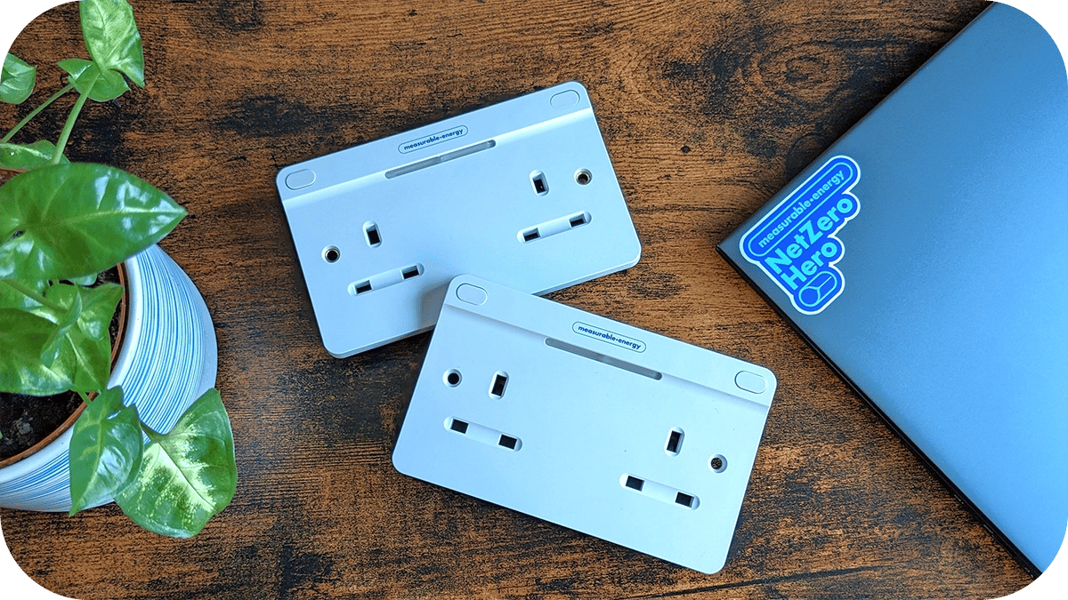 Two measurable.energy double gang plug sockets on a dark wood table.