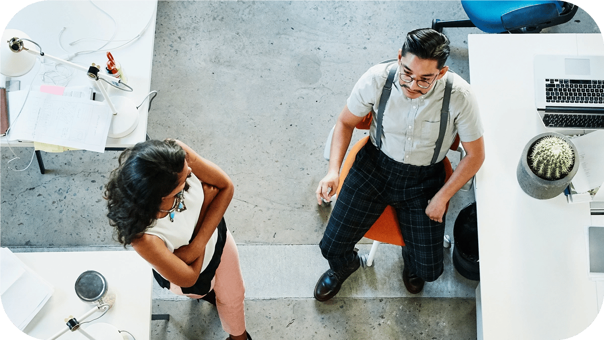 A view from above of a well-lit office, with two people having a conversation.