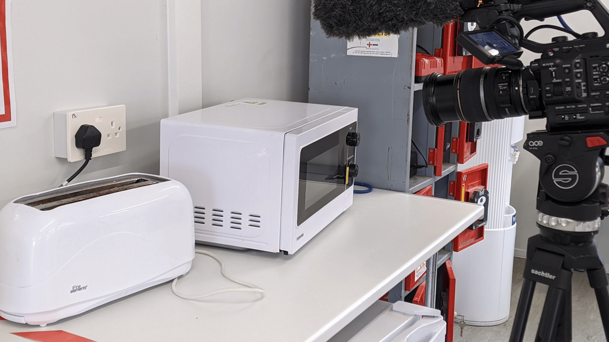 A toaster plugged into a measurable.energy socket, with a microwave and camera to the right.