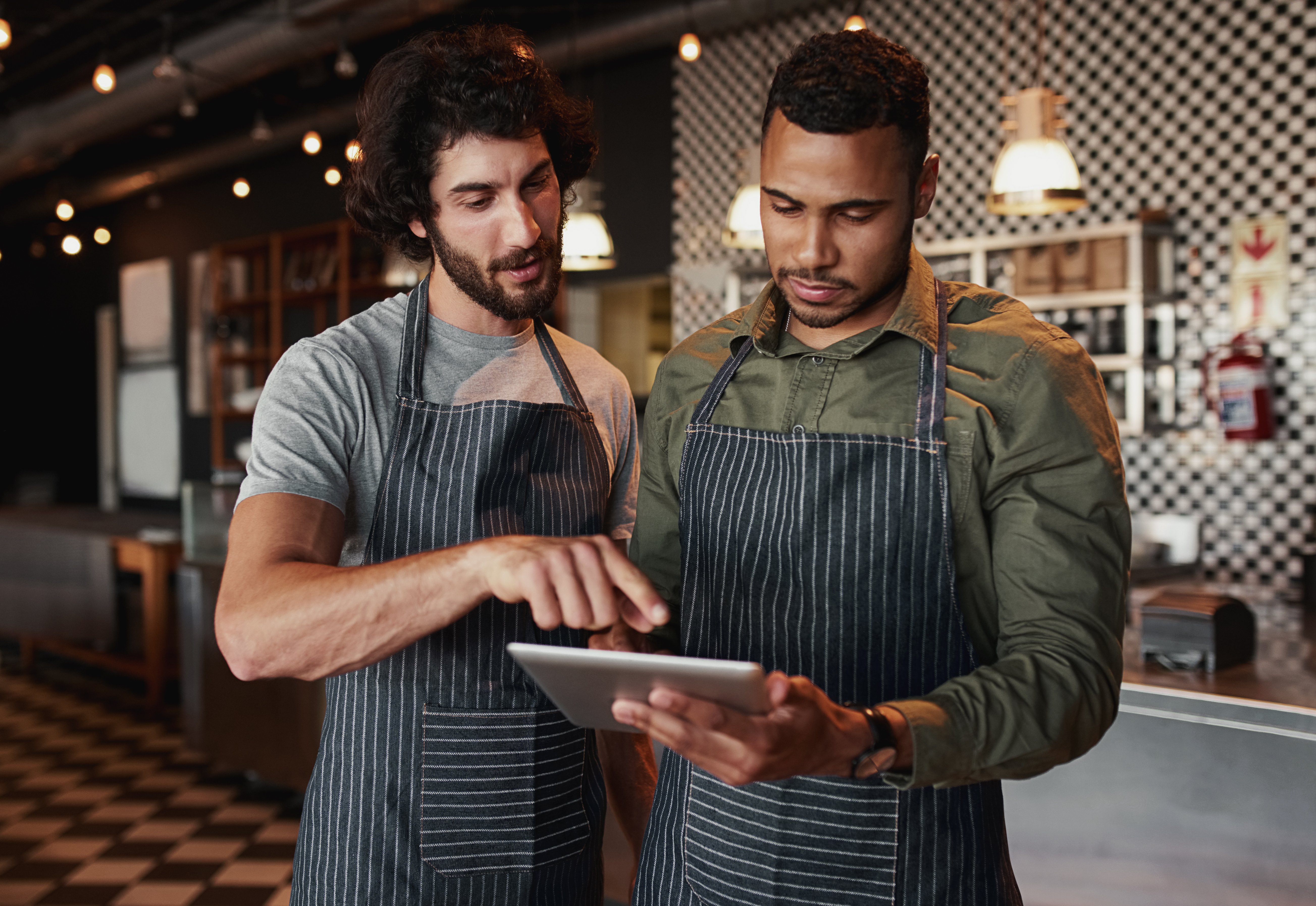 Two male restaurant workers looking at information on a tablet