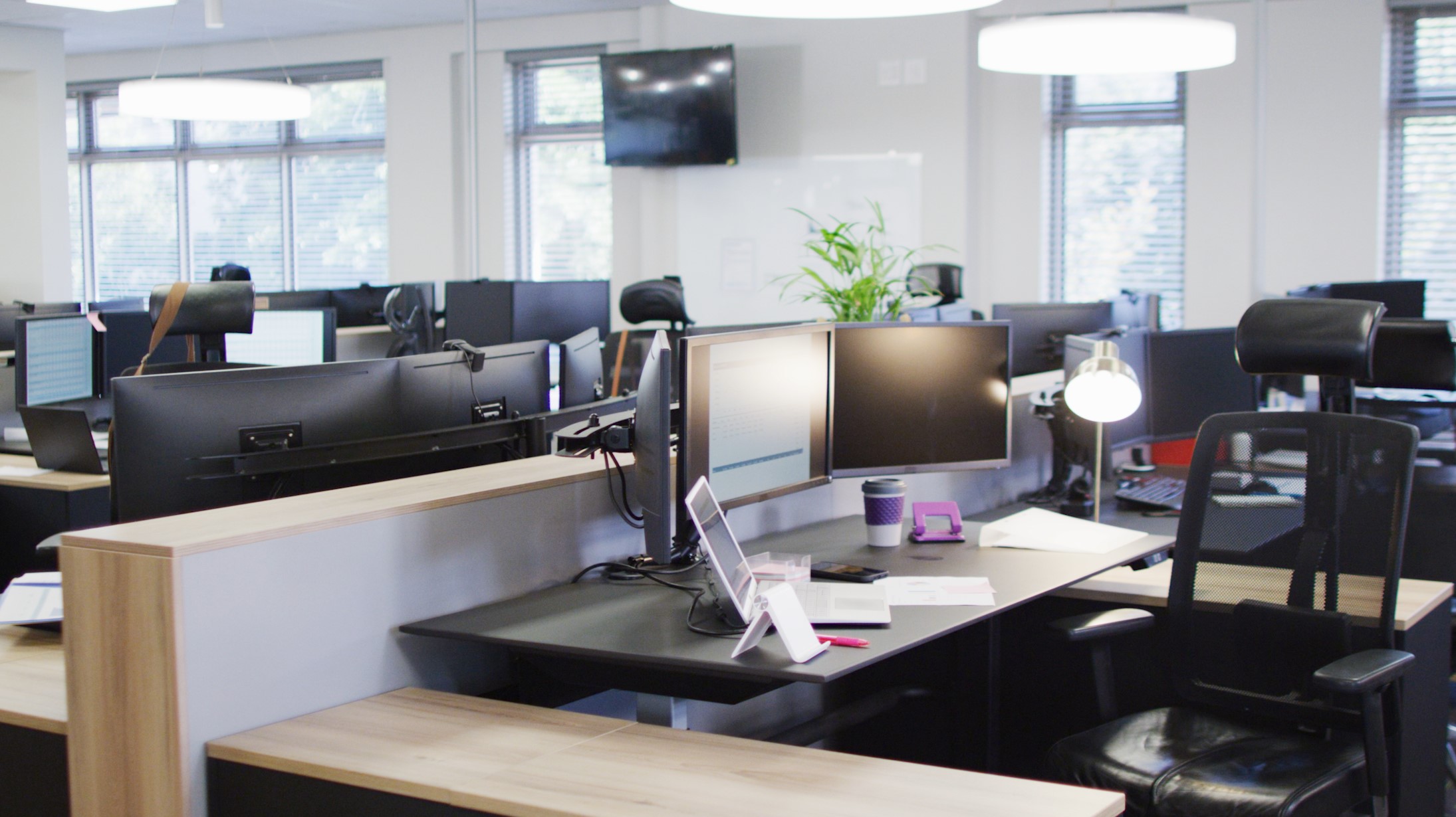 An empty office space with monitors and desk lamp on the desk. 