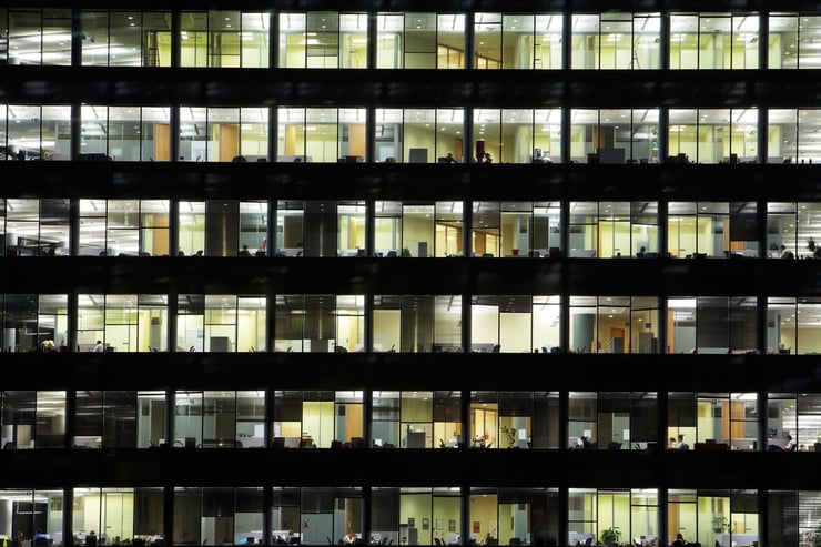 window of the multi-storey building of glass and steel office lighting and working people within